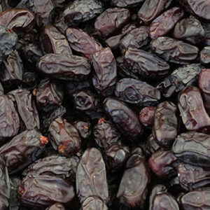 A close-up view of a pile of dark, dried dates with a glossy skin.