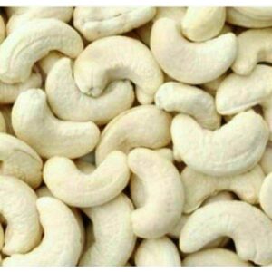 A close-up image of raw, unroasted cashew nuts scattered on a surface.
