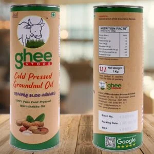 A cylindrical container of cold pressed groundnut oil, labeled "ghee STORE," featuring a cow illustration and text in both English and Tamil. The container includes nutritional facts on one side, with details on the product's weight (1 kg) and packaging information. It showcases a natural, earthy design with peanuts depicted at the bottom.