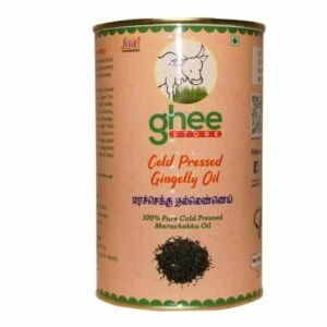 A cylindrical tin of cold pressed gingelly oil, featuring a cow graphic and text in both English and Tamil. The label indicates it is 100% pure and cold pressed, with a decorative border at the top.