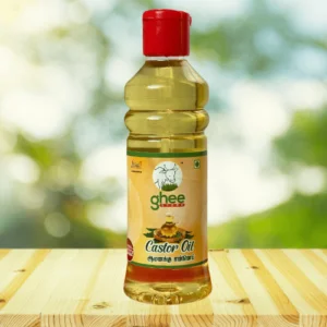 Bottle of castor oil with a red cap, featuring a label with text in English and another script, set on a wooden surface with a blurred green background.