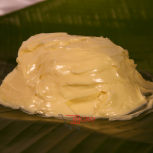 A rounded mound of creamy butter on a green banana leaf.