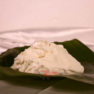 A creamy white substance placed on a green banana leaf, with a blurred background.